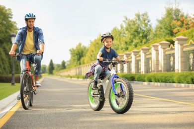 Photo of Dad and son riding modern bicycles outdoors