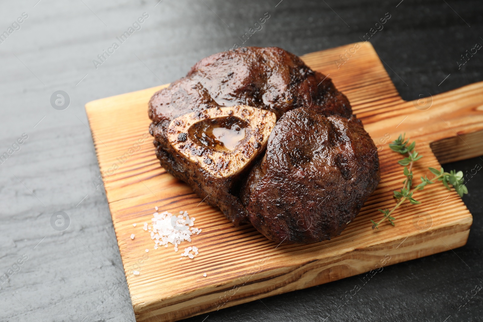 Photo of Piece of delicious grilled beef meat, thyme and salt on black table