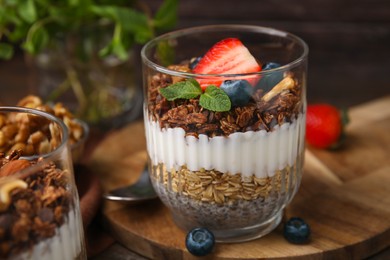 Photo of Tasty granola with berries, yogurt and chia seeds in glass on table, closeup