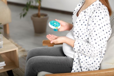 Photo of Pregnant woman taking pill from container at home, closeup