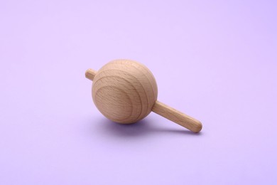 Photo of One wooden spinning top on lilac background. Toy whirligig