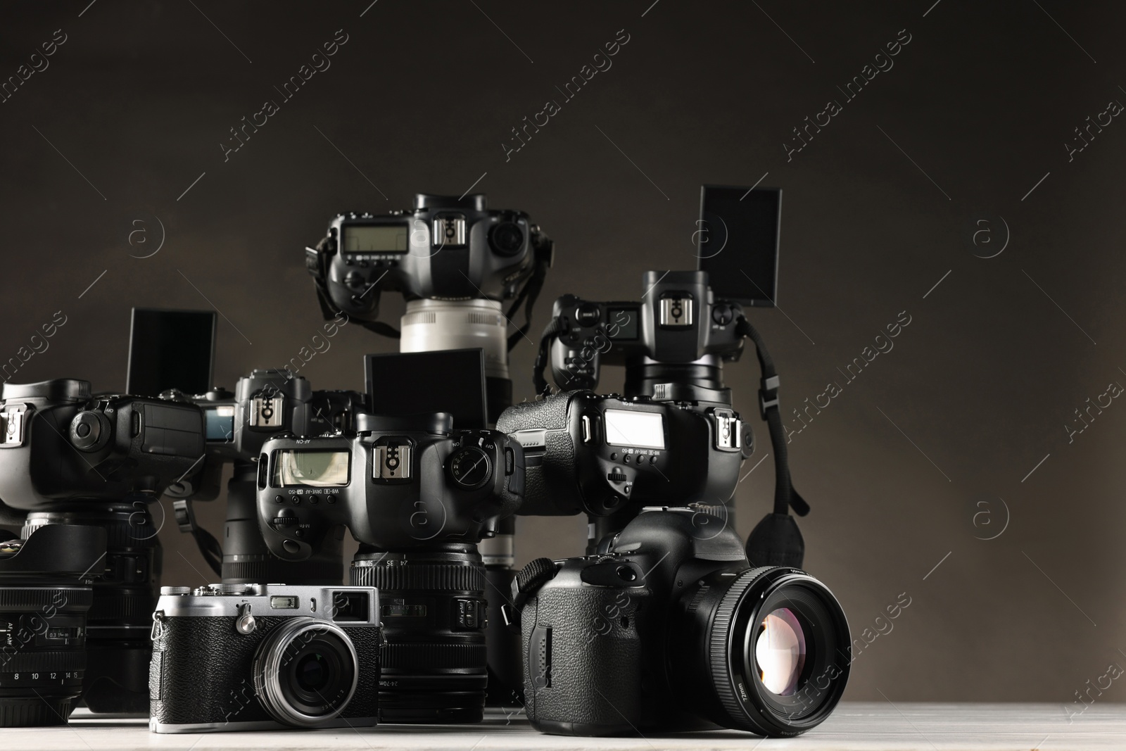 Photo of Modern cameras on white table against dark background