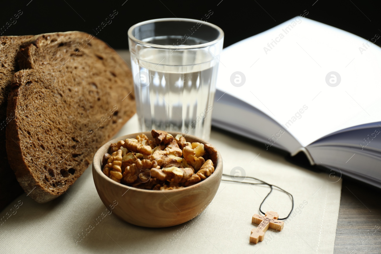 Photo of Bread, walnuts, water, Bible and crucifix on table. Great Lent season