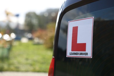 L-plate on car outdoors, closeup with space for text. Driving school