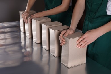 People packing cardboard boxes at production line, closeup