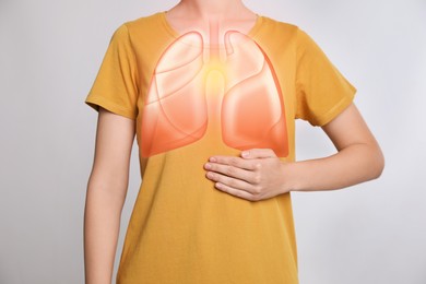 Image of Woman holding hand near chest with illustration of lungs against grey background, closeup