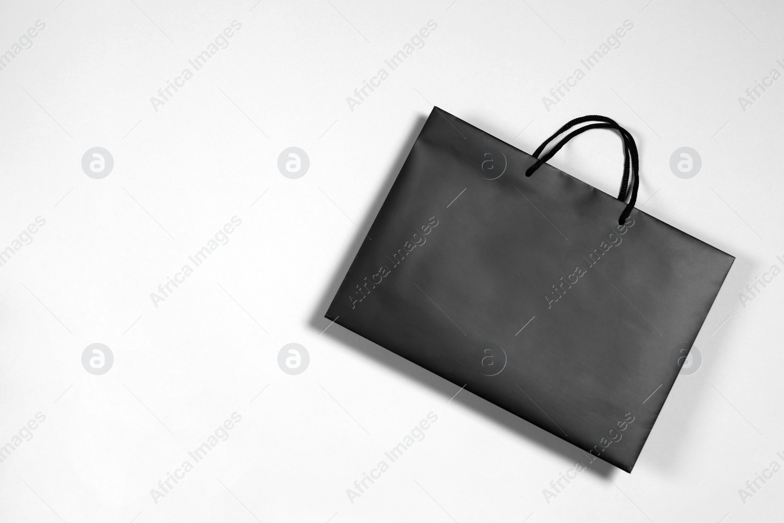 Photo of One black paper shopping bag on grey background, top view. Space for text