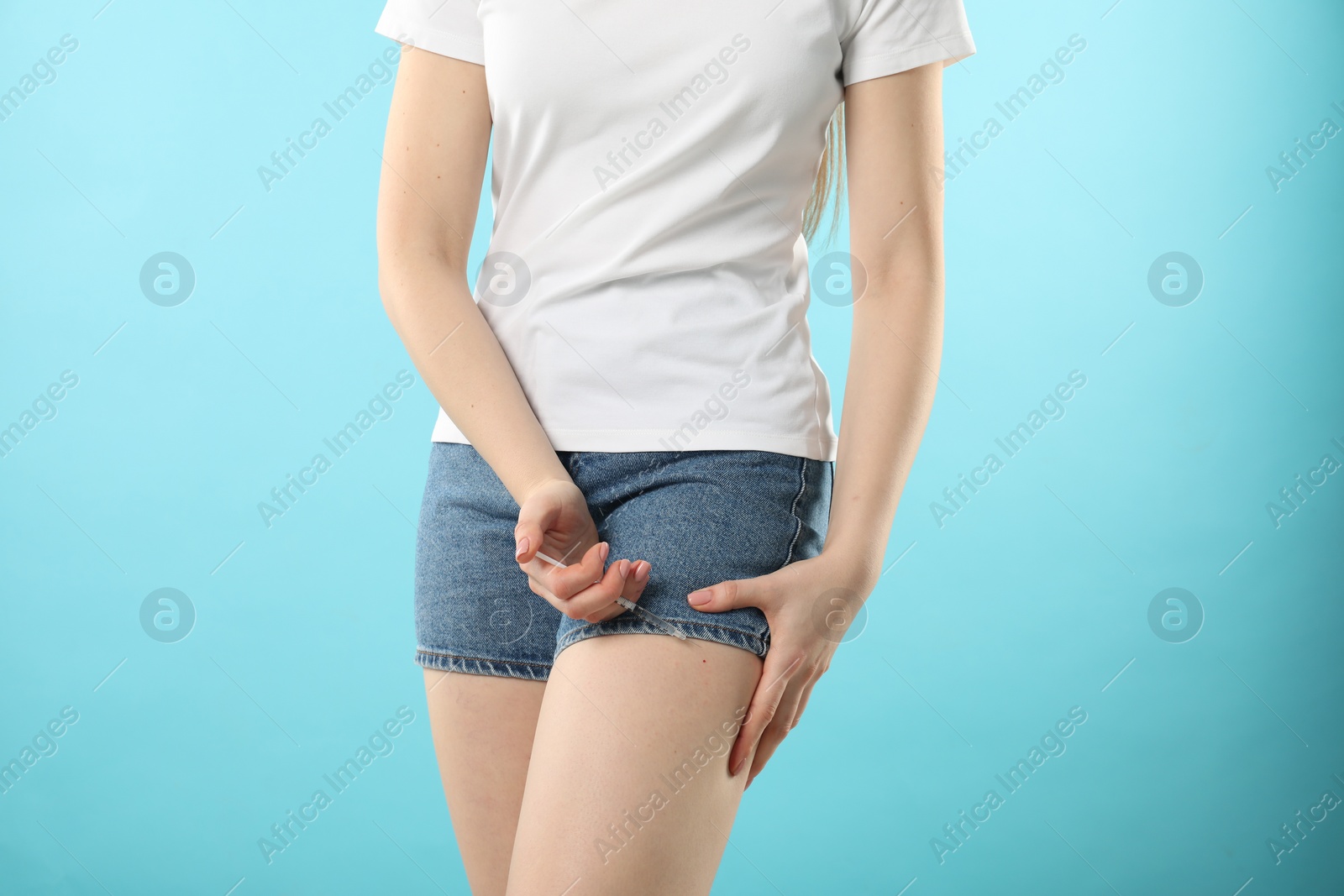 Photo of Diabetes. Woman making insulin injection into her leg on light blue background, closeup