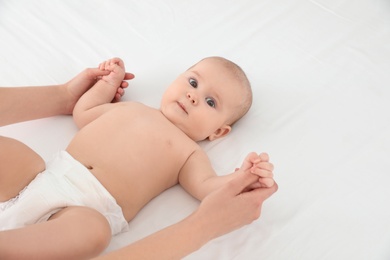Photo of Mother and her cute child on white bed, space for text. Baby massage and exercises