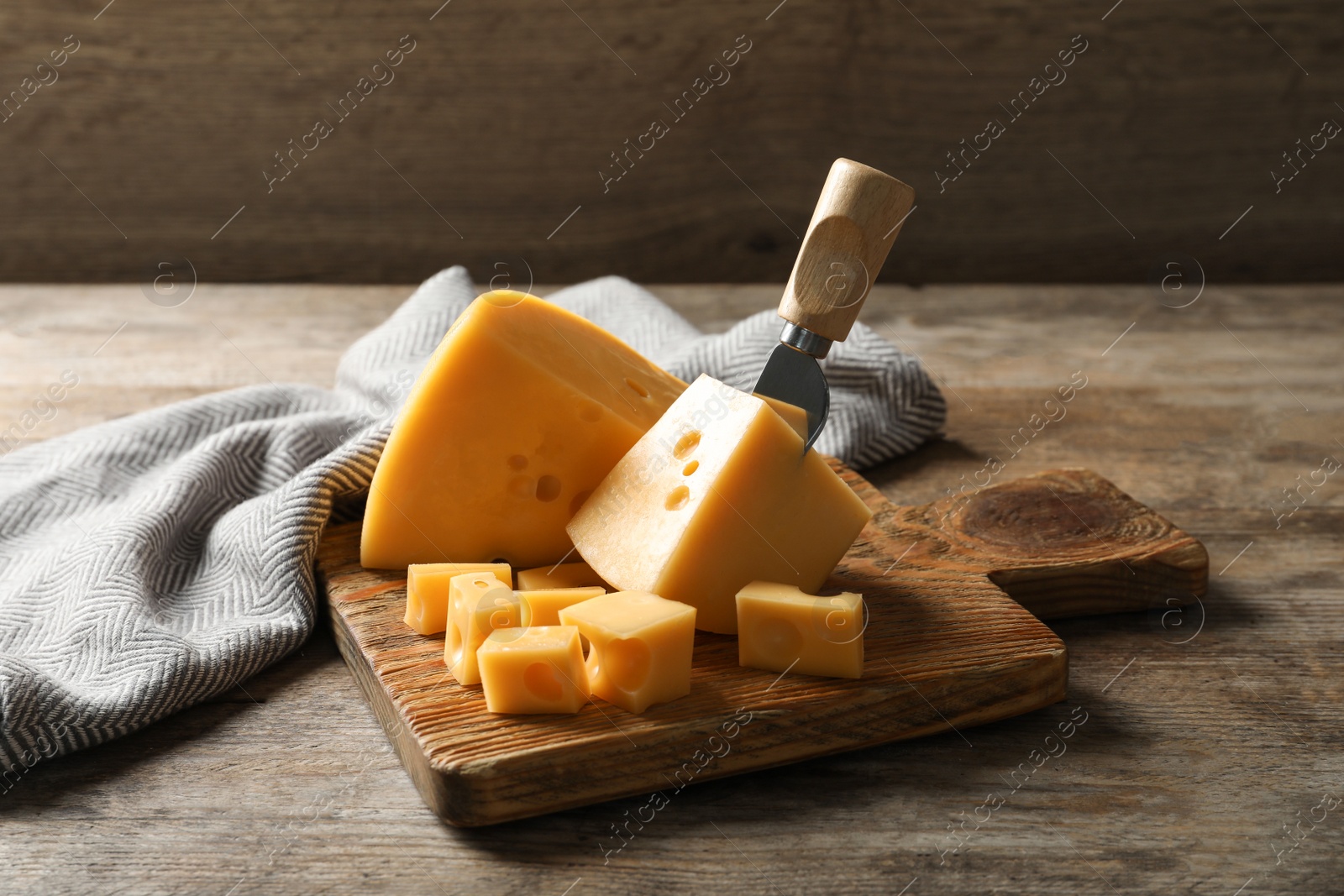 Photo of Serving board with delicious cheese on wooden table