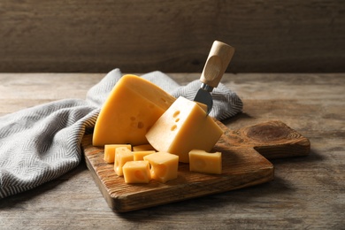 Photo of Serving board with delicious cheese on wooden table