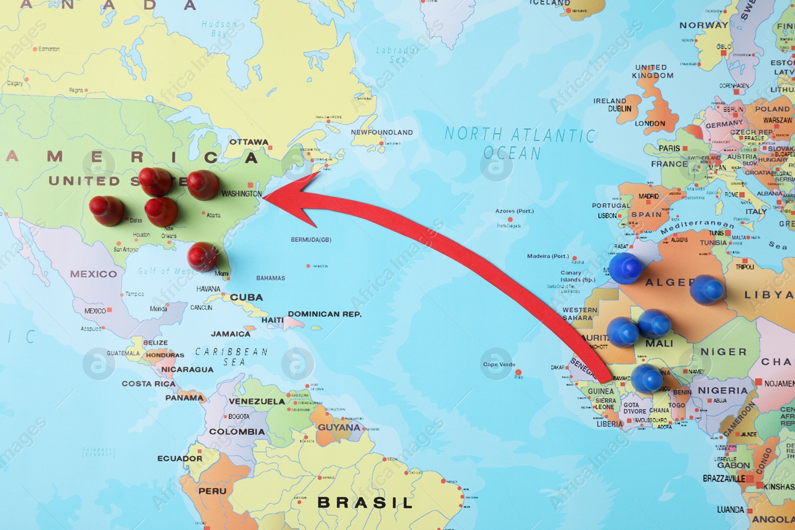 Photo of World map with red, blue pawns and arrow pointing on USA, top view