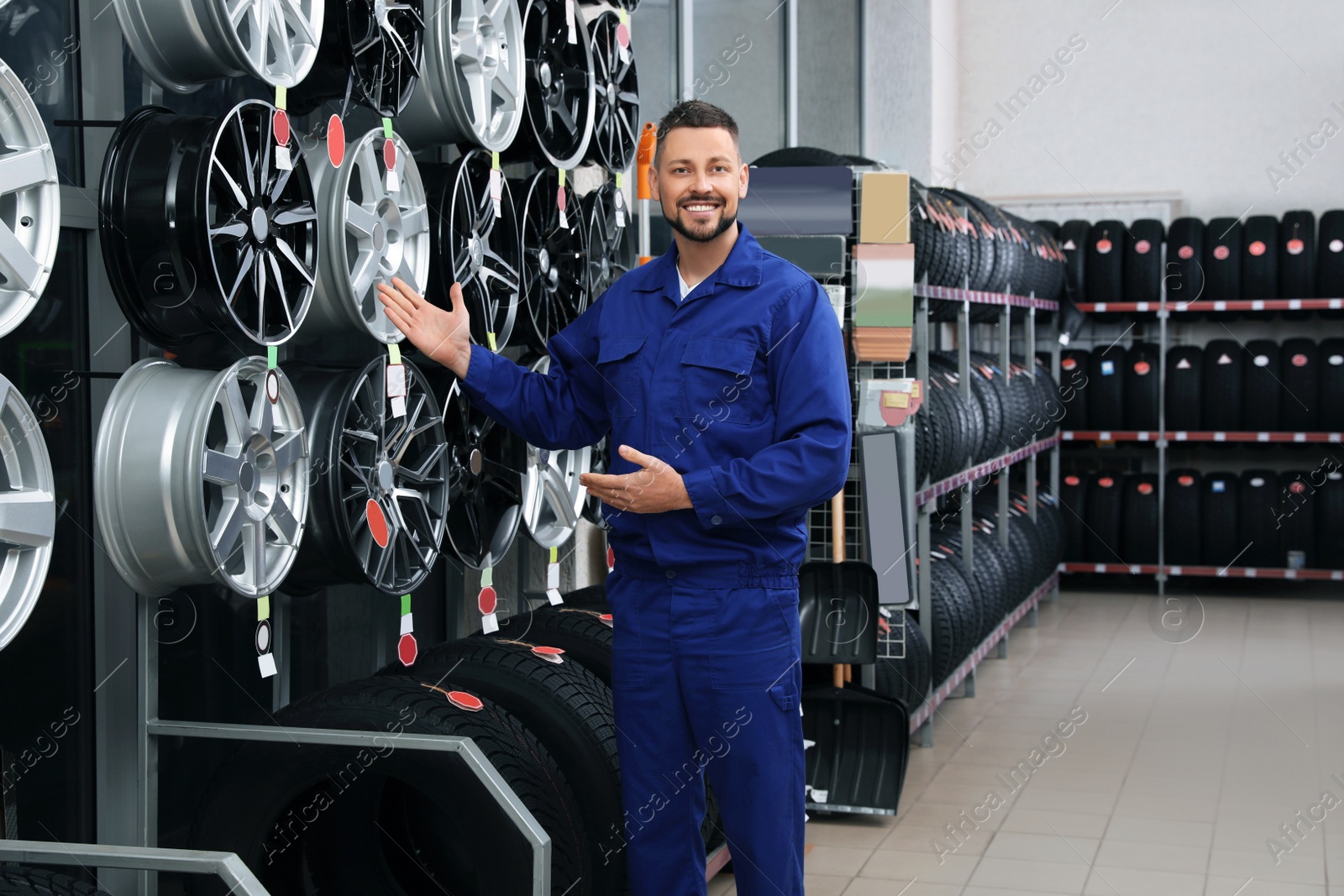 Photo of Male mechanic near car tires and alloy wheels in auto store