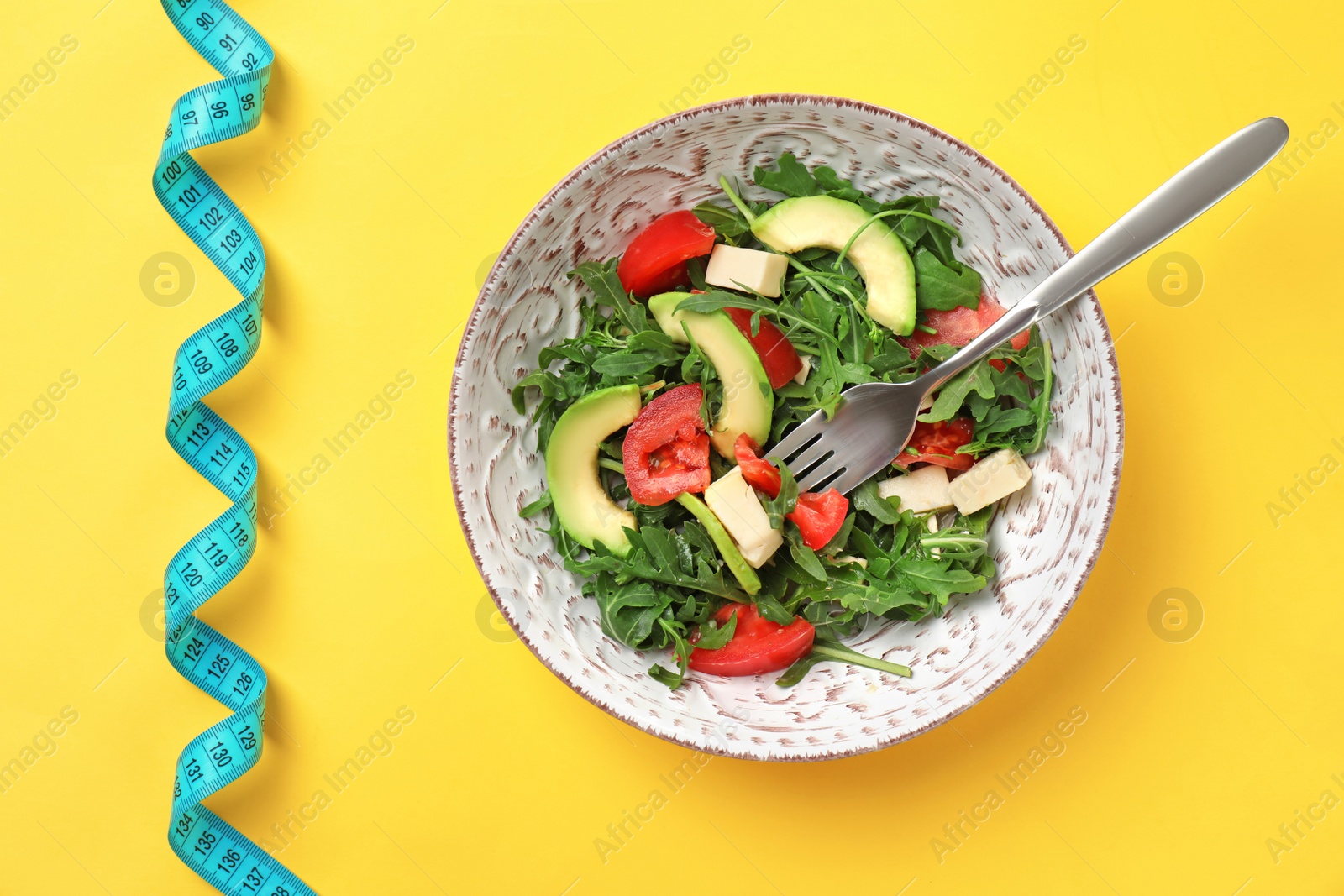 Photo of Bowl with fresh vegetable salad and measuring tape on color background, top view. Healthy diet