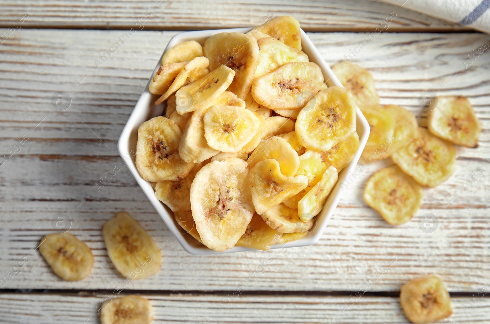 Photo of Bowl with sweet banana slices on wooden  table, top view. Dried fruit as healthy snack