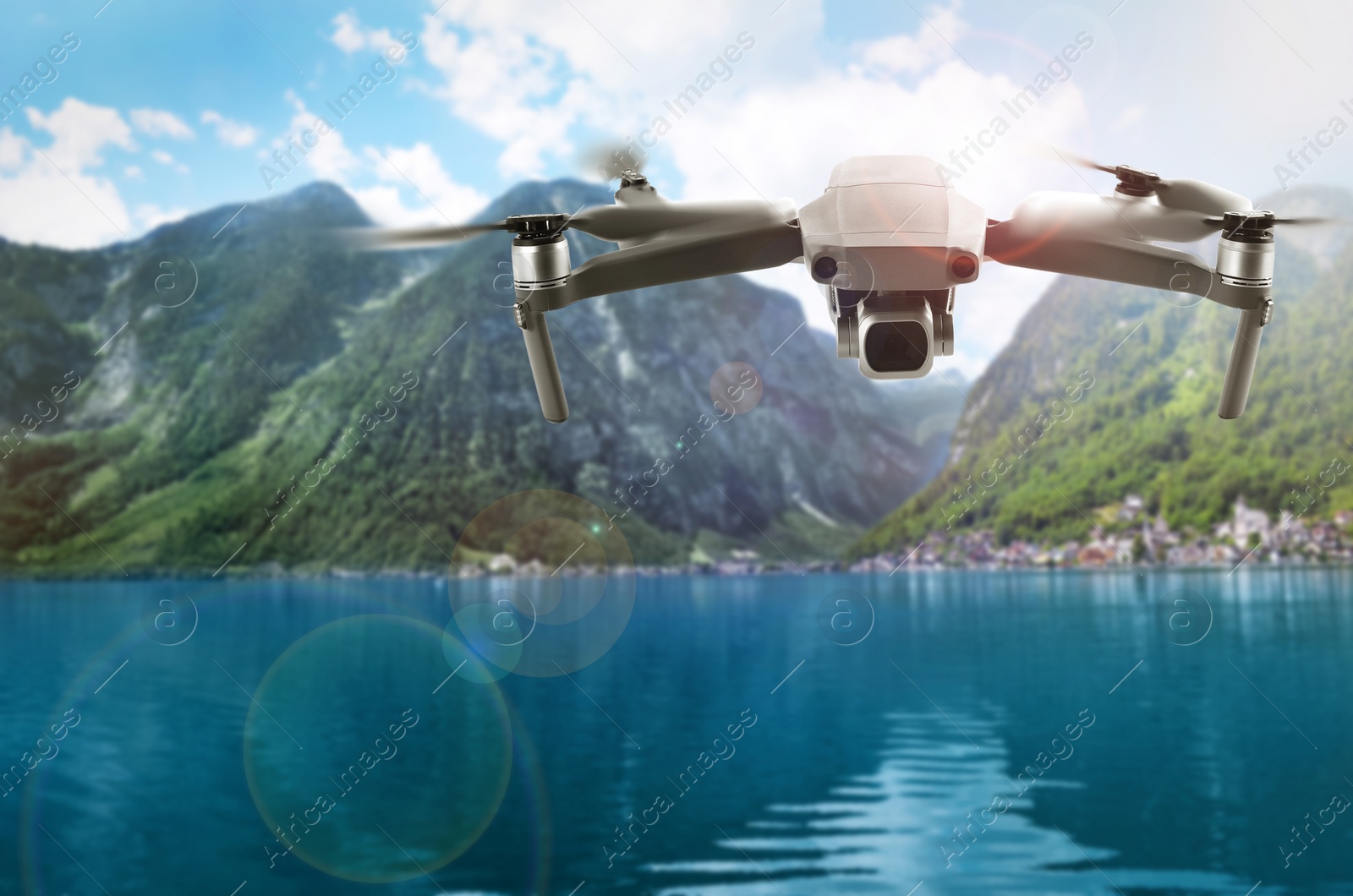 Image of Modern drone flying over lake near picturesque mountains. Aerial survey