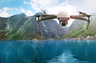 Image of Modern drone flying over lake near picturesque mountains. Aerial survey