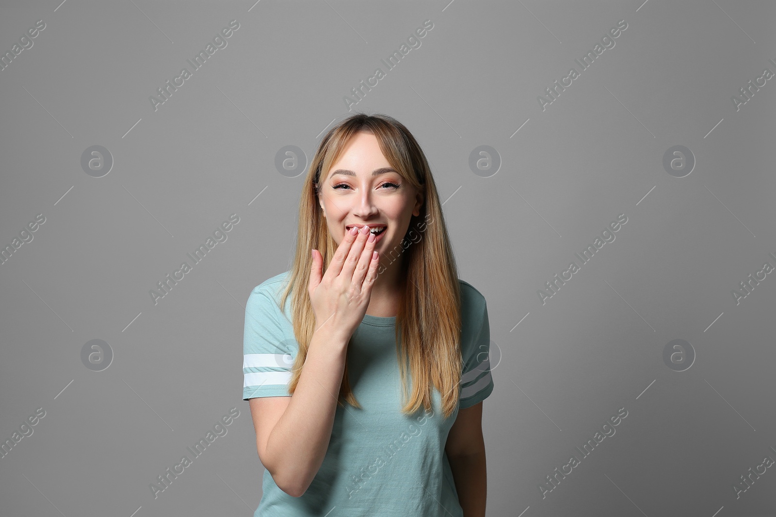 Photo of Beautiful young woman laughing on grey background. Funny joke