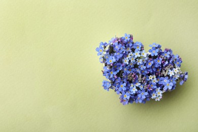 Photo of Heart of beautiful blue forget-me-not flowers on light green background, top view. Space for text