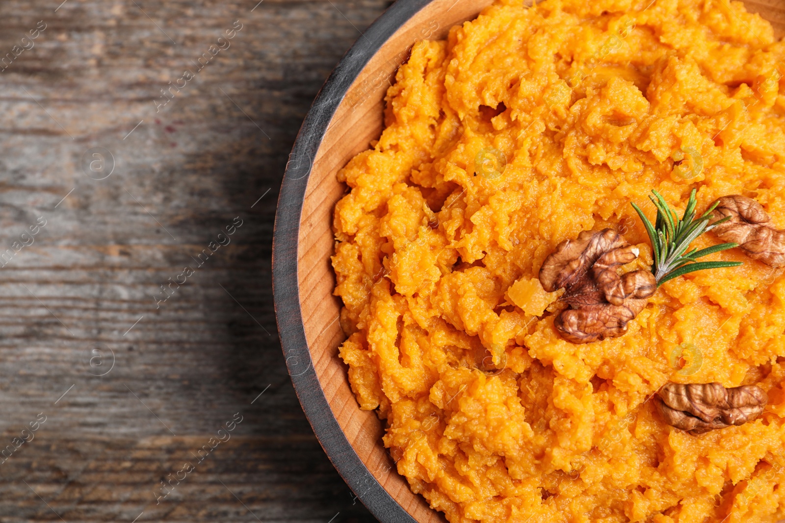 Photo of Bowl with mashed sweet potatoes on wooden table, top view. Space for text