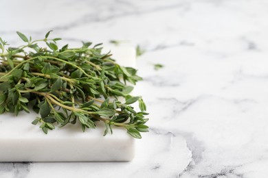 Bunch of aromatic thyme on white marble table, closeup. Space for text