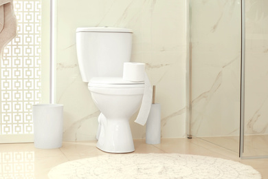 Photo of Modern toilet bowl with roll of paper in bathroom