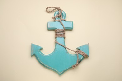 Wooden anchor with hemp rope on beige background, top view