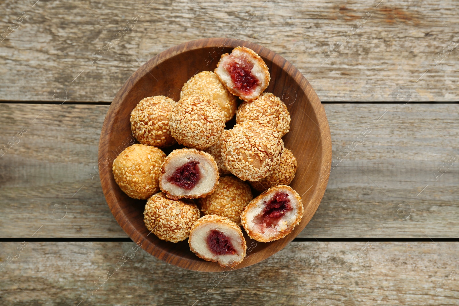 Photo of Delicious sesame balls with red bean paste on wooden table, top view