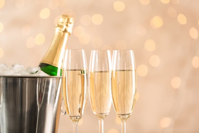 Glasses with champagne and bottle in bucket against blurred lights