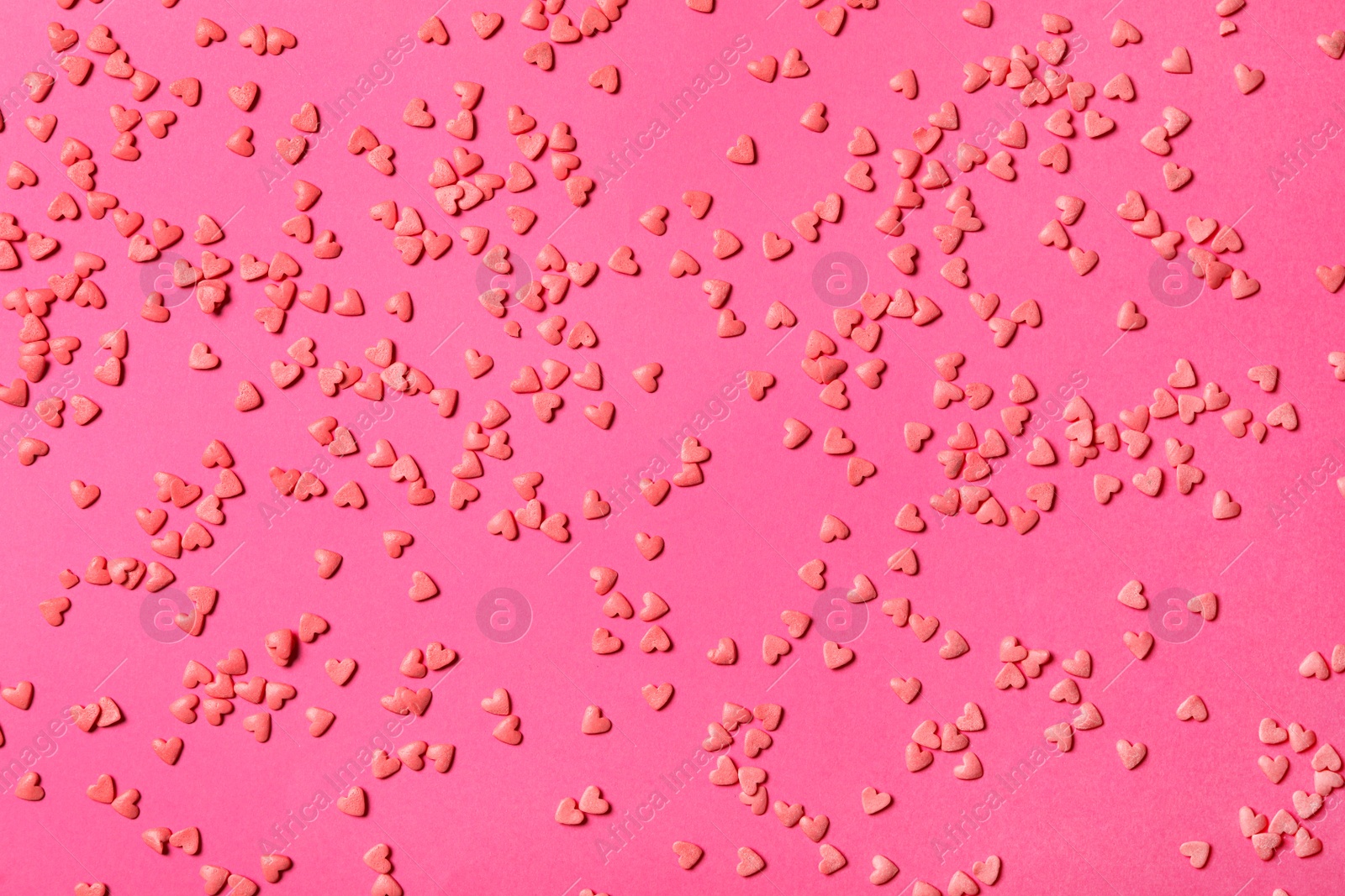 Photo of Heart shaped sprinkles on pink background, flat lay