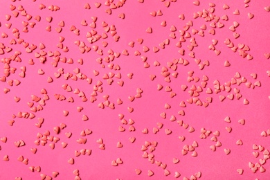 Heart shaped sprinkles on pink background, flat lay