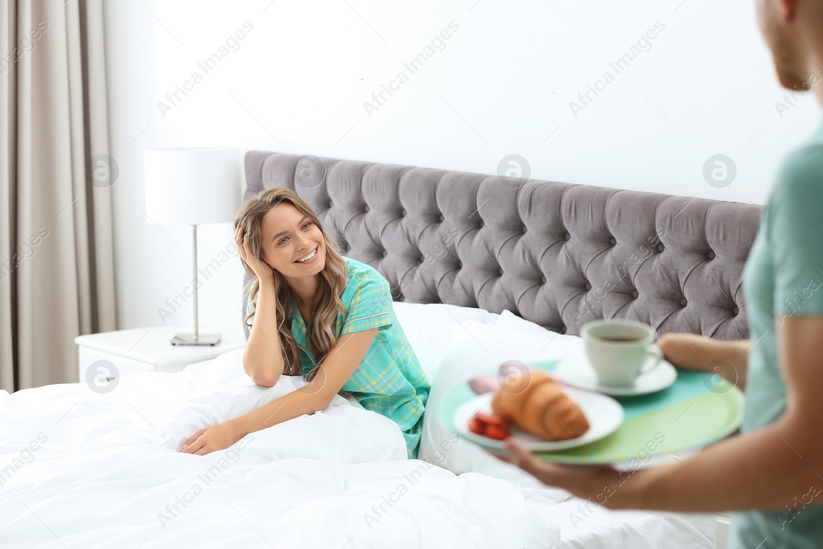 Photo of Young man bringing romantic breakfast to his girlfriend in bed at home