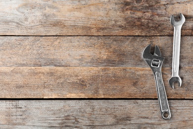 Photo of New wrenches on wooden background, top view with space for text. Plumber tools