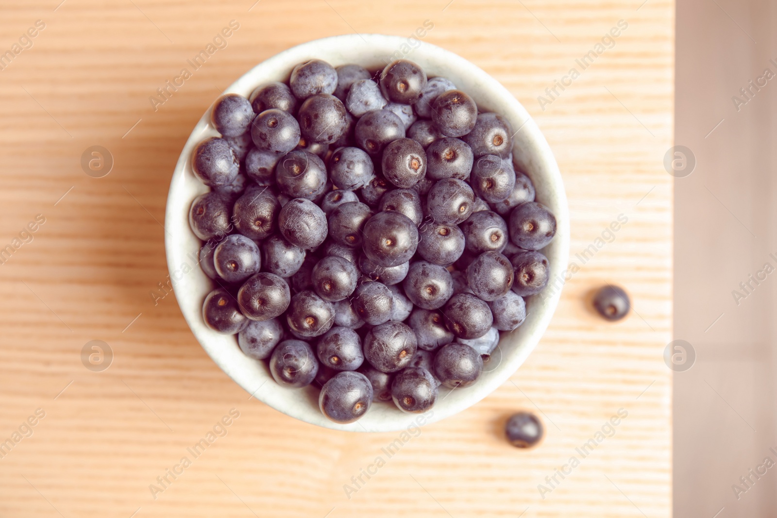 Photo of Bowl with fresh acai berries on table, top view