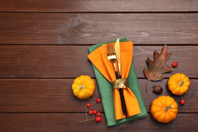 Photo of Cutlery, napkins and autumn decoration on wooden background, flat lay with space for text. Table setting