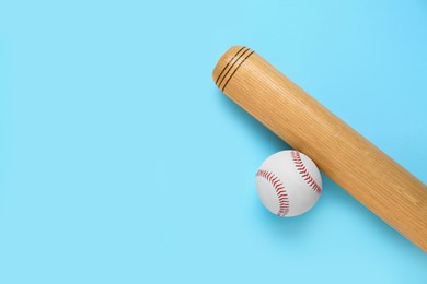 Photo of Wooden baseball bat and ball on light blue background, flat lay. Space for text