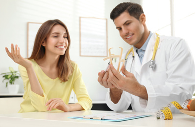 Nutritionist consulting patient at table in clinic, focus on hands