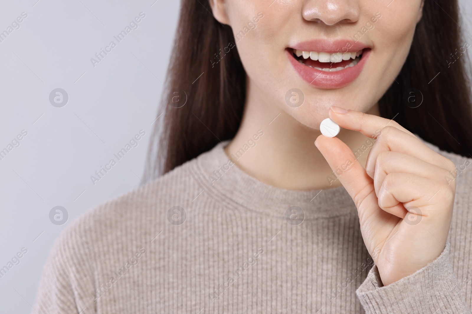 Photo of Woman taking pill on gray background, closeup