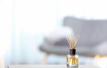 Photo of Aromatic reed air freshener on table against blurred background