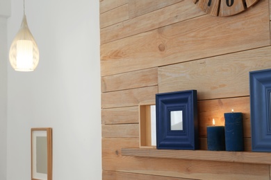 Photo of Shelf with burning candles against wooden wall