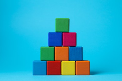 Photo of Pyramid of blank colorful cubes on light blue background