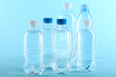 Set of different plastic bottles with water on blue background