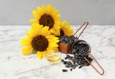 Photo of Sunflowers, oil and seeds on white marble table