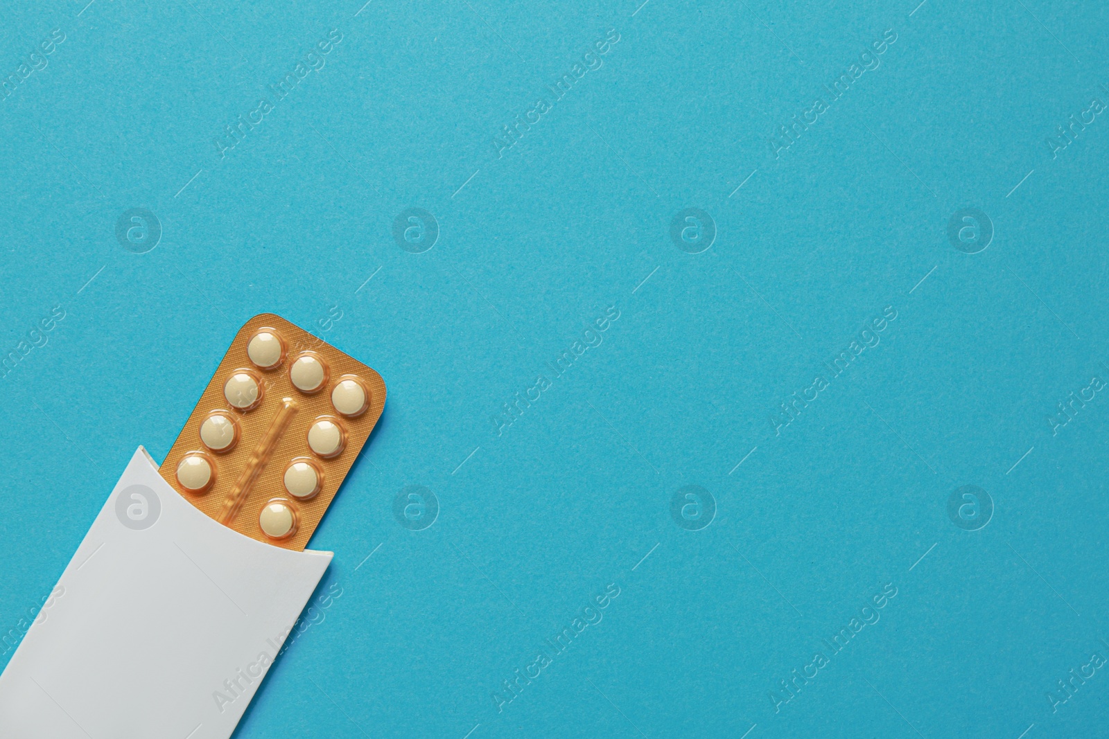 Photo of Birth control pills on light blue background, top view. Space for text