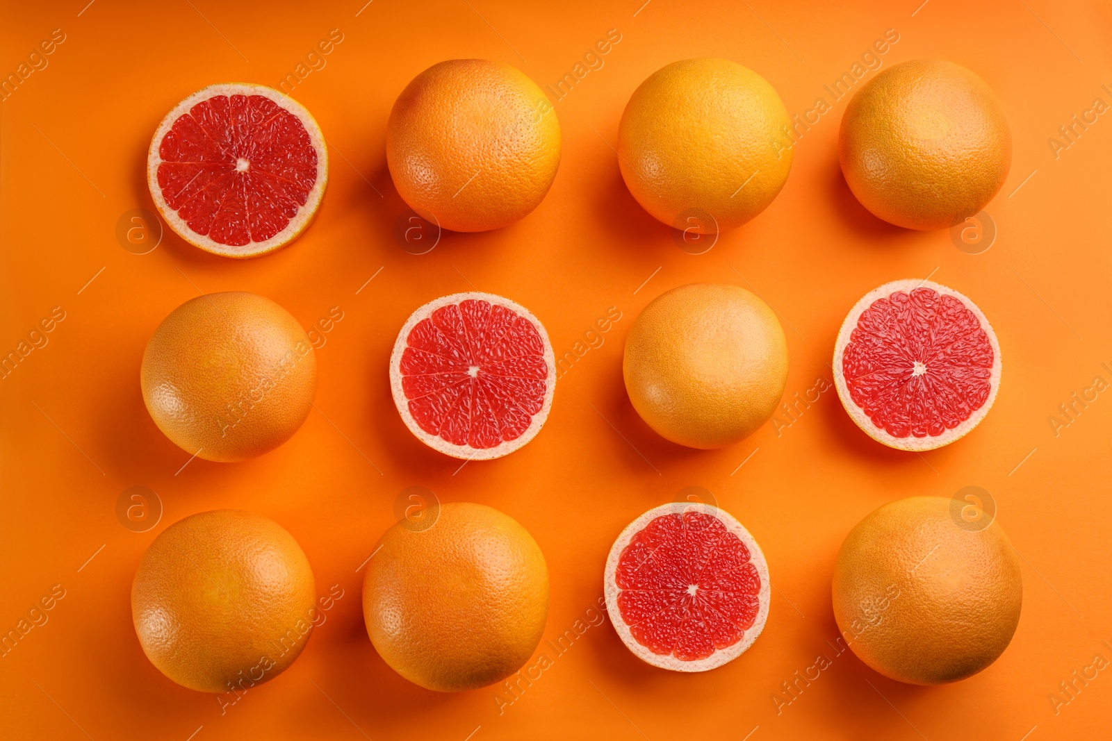 Photo of Cut and whole ripe grapefruits on orange background, flat lay