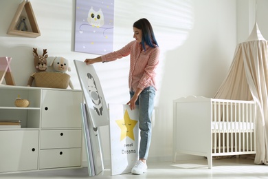 Photo of Decorator with pictures near white wall. Children's room interior design