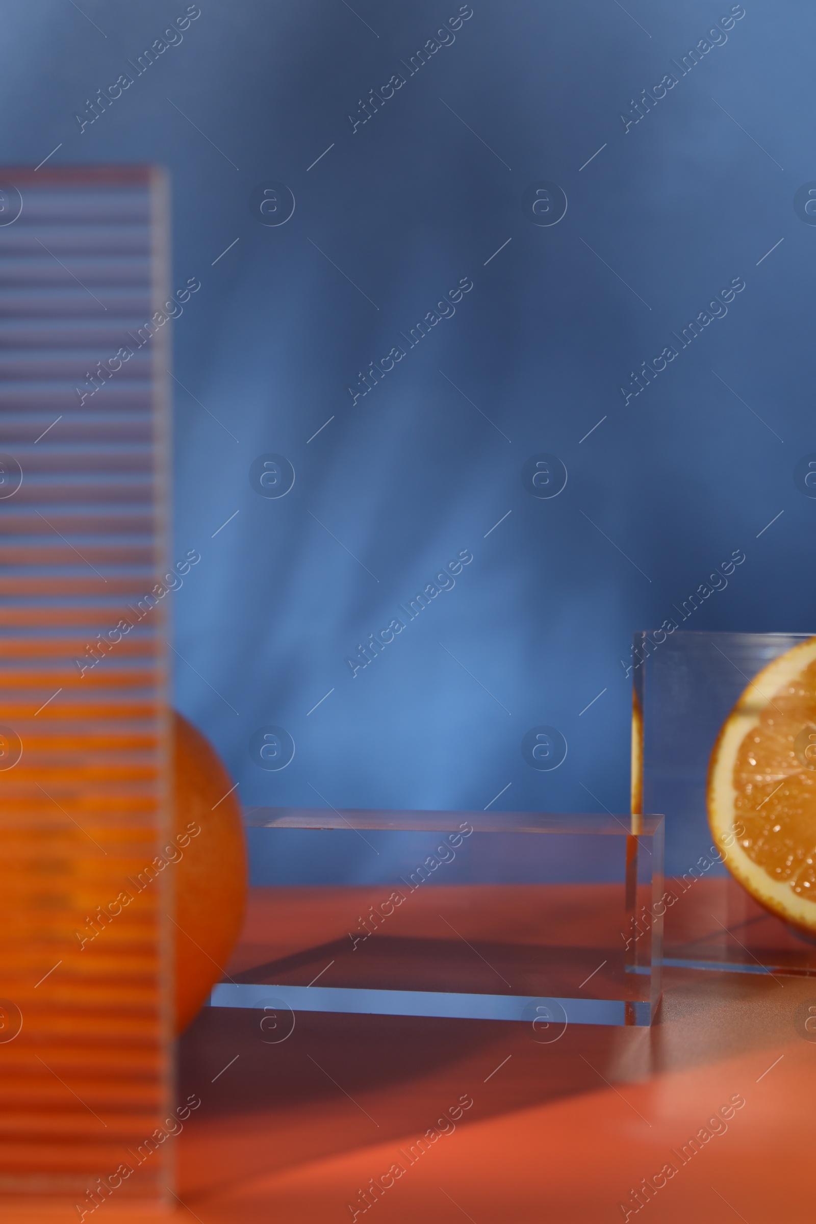 Photo of Presentation for product. Podium and tasty fresh oranges on red table against blue background, closeup. Space for text