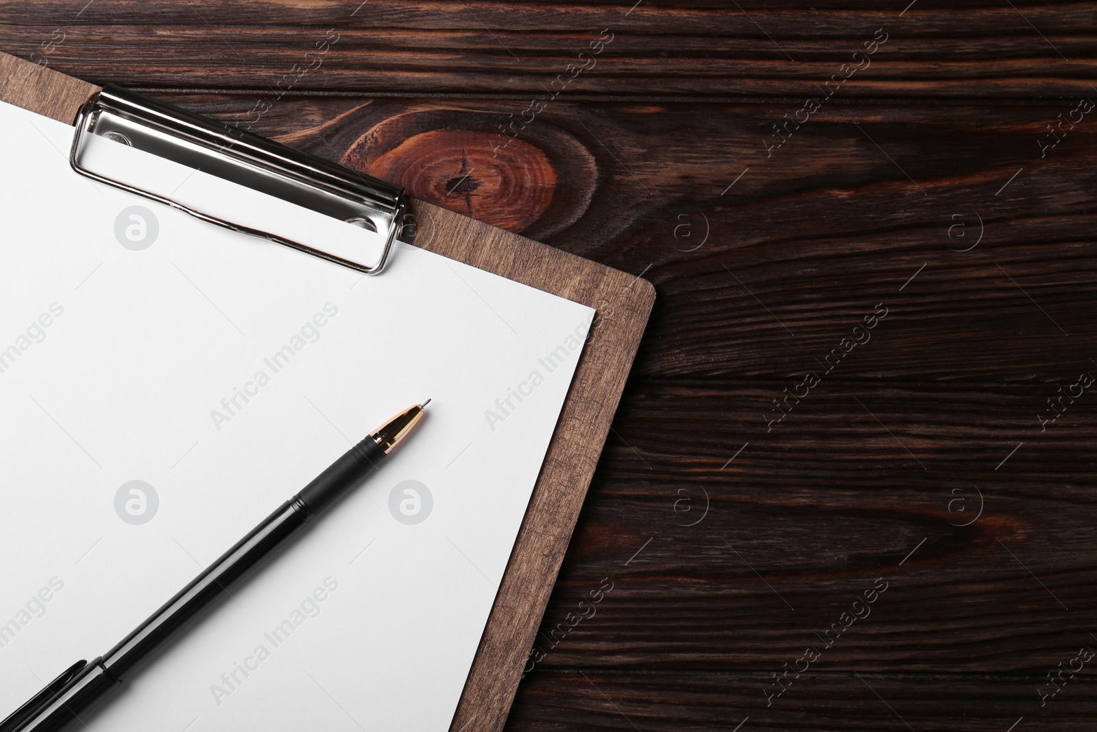 Photo of New clipboard with sheet of blank paper and pen on wooden table, top view. Space for text