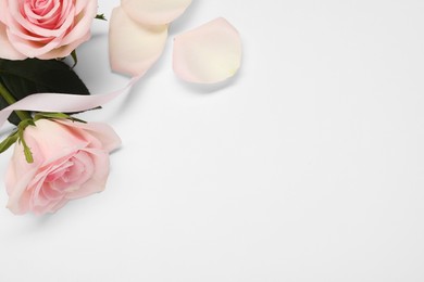 Photo of Beautiful roses, ribbon and petals on white background, flat lay. Space for text