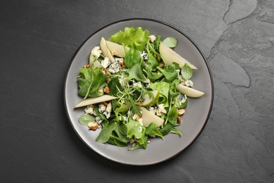 Photo of Tasty salad with pear slices on black table, top view